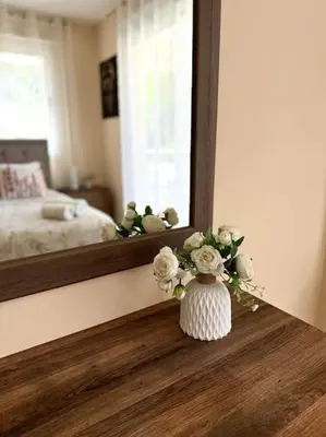 a vase with flowers sitting on a table in front of a mirror at NISSI BEACH Apt 7 BIG VERANDA AND FREE WIFI in Ayia Napa
