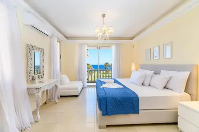a bedroom with a bed and a view of the ocean at Royal Beachfront Villa in Protaras