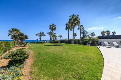 a large lawn with palm trees and a building at Royal Beachfront Villa in Protaras