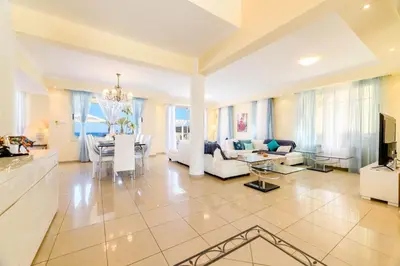 a large living room with white furniture and a table at Royal Beachfront Villa in Protaras