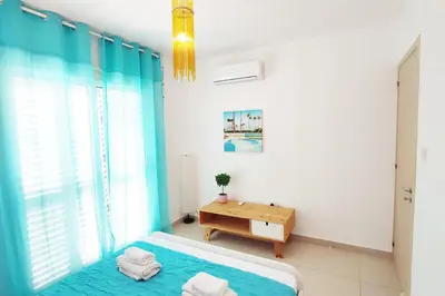 a bedroom with a bed and a table and a window at Nissini Shell, 3 bedroom villa with private pool at Nissi Beach in Ayia Napa