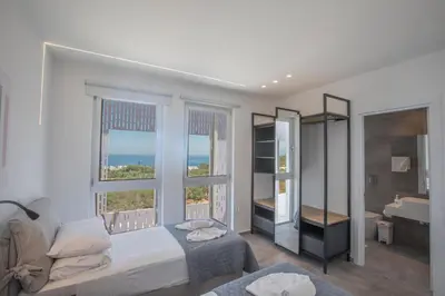 a bedroom with a bed and two windows and a bathroom at Chloe Luxury Villas in Protaras