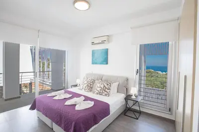 a white bedroom with a large bed and a balcony at Chloe Luxury Villas in Protaras