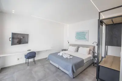 a bedroom with a bed and a chair and a tv at Chloe Luxury Villas in Protaras
