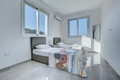 a bedroom with two beds and two windows at Chloe Luxury Villas in Protaras