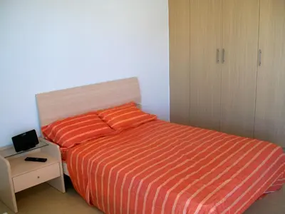 a bedroom with a bed with a orange striped blanket at A209 Coralli Spa, Cyprus - Med View Studio in Protaras
