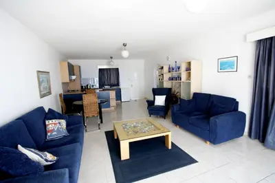 a living room with blue couches and a table at Pissouri Beach Apartments in Pissouri