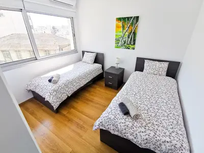 two beds in a room with two windows at Daze Off Central Apartment, 300m to the Finikoudes Beach in Larnaka