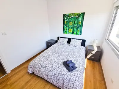 a bedroom with a bed with a comforter at Daze Off Central Apartment, 300m to the Finikoudes Beach in Larnaka