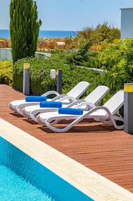a row of white lounge chairs next to a swimming pool at Seafront Villa Maya by Ruidoso Luxury in Ayia Napa