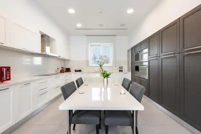 a white kitchen with a white table and chairs at Seafront Villa Maya by Ruidoso Luxury in Ayia Napa