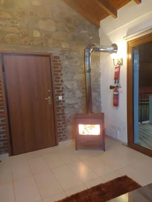 a wood stove in a room with a stone wall at Love Holiday Suite 1 in Tris Elies