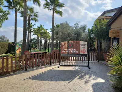 a sign in front of a fence with palm trees at MERSINERA PARADISE GARDEN STARS HOUSE in Larnaka