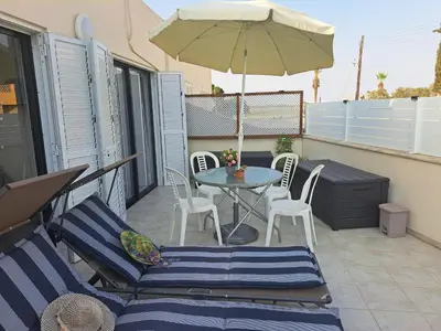a patio with a table and chairs and an umbrella at House Near The Beach (Militsa & Aggeliki) in Pervolia