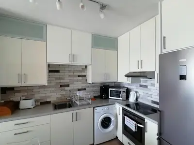 a kitchen with white cabinets and a washer at Sunorama Waterfront Apartment in Larnaka
