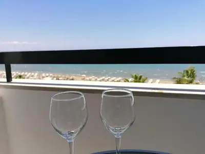 two wine glasses sitting on a table in front of a window at Sunorama Waterfront Apartment in Larnaka