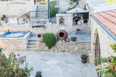 an outdoor patio with a stone fireplace and an outdoor oven at Our House in Vavla