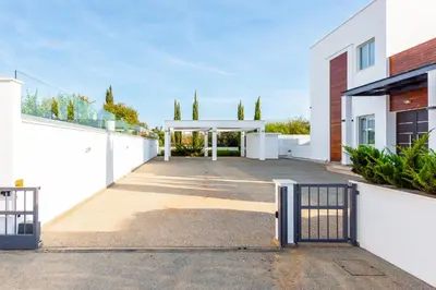 a white building with a gate in a driveway at Seafront Villa Cecelia by Ruidoso Luxury in Ayia Napa