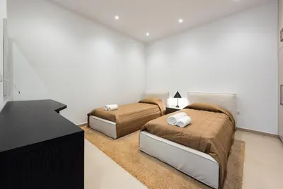 two beds in a white room with a desk and a room with two beds at Seafront Villa Cecelia by Ruidoso Luxury in Ayia Napa
