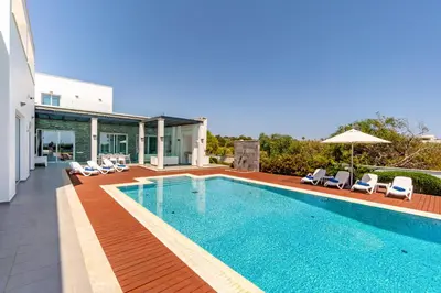 a swimming pool with chairs and a house at Seafront Villa Cecelia by Ruidoso Luxury in Ayia Napa