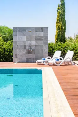 a swimming pool with lounge chairs next to a bathroom at Villa Dione by Ruidoso Luxury in Ayia Napa