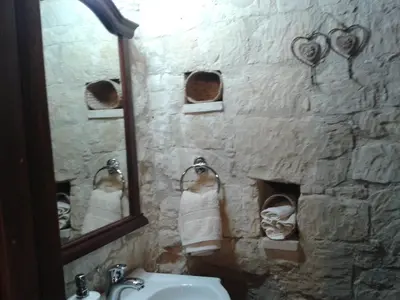 a stone bathroom with a sink and a mirror at Magdalous House in Arsos