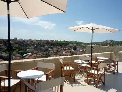 a balcony with tables and chairs and umbrellas at Apokryfo Traditional Guesthouse in Lofou
