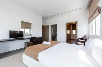 a white bedroom with a large bed and a kitchen at Villa Marsali by Ruidoso Luxury in Ayia Napa