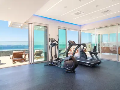 a gym with two tread machines in a room with windows at The Tower at St Raphael Resort in Limassol