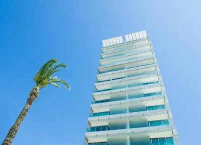a tall building with a palm tree in front of it at The Tower at St Raphael Resort in Limassol