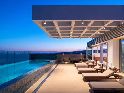 a swimming pool with chaise lounges on the side of a building at The Tower at St Raphael Resort in Limassol