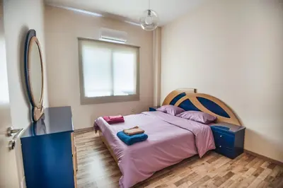 a bedroom with a bed with purple sheets and a mirror at Orion Apartment 401 in Larnaka