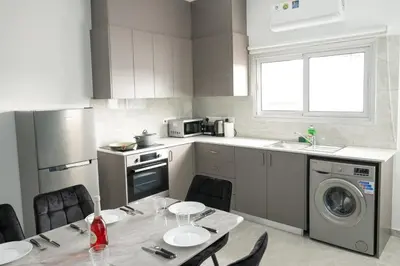 a kitchen with a table with chairs and a sink at Bellagio Napa Suites in Ayia Napa