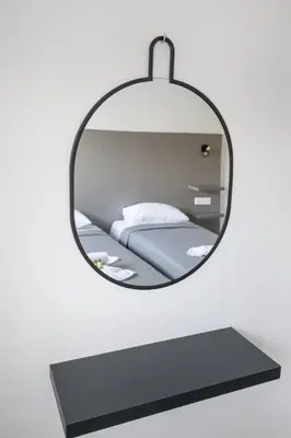 a mirror hanging on a wall with a bed at Bellagio Napa Suites in Ayia Napa