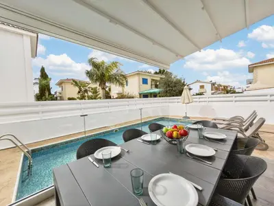 a dining room with a table and chairs and a pool at Elite Luxury Villa in Paralimni