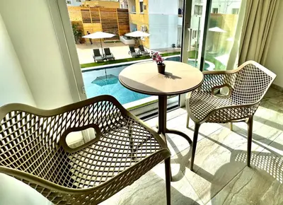 two chairs and a table in a room with a window at Sun Plaza Suites - Adults Only in Ayia Napa