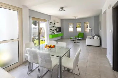 a dining room with a glass table and white chairs at Protaras Palm Villa 54 in Protaras