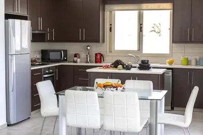 a kitchen with white chairs and a table and a refrigerator at Protaras Palm Villa 54 in Protaras