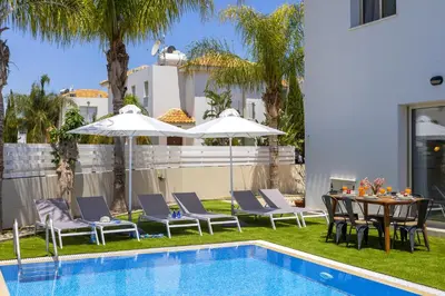 a backyard with a table and chairs and a pool at Protaras Palm Villa 54 in Protaras