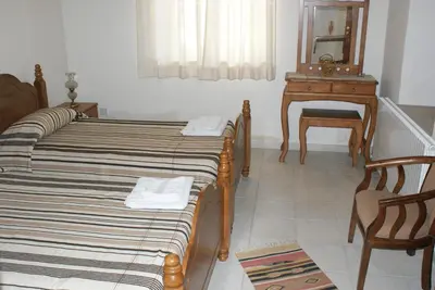 a room with two beds and a table and a mirror at ATRATSA Mountain Suites in Kalopanayiotis