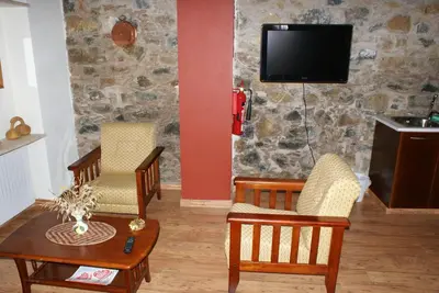 a living room with chairs and a table and a tv at ATRATSA Mountain Suites in Kalopanayiotis