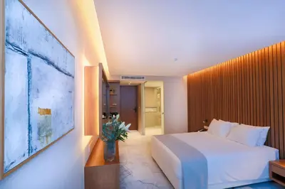 a hotel room with a white bed and a tv at Radisson Beach Resort Larnaca in Larnaka