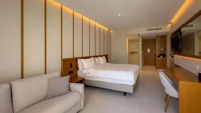 a bedroom with a bed and a couch and a sink at Radisson Beach Resort Larnaca in Larnaka