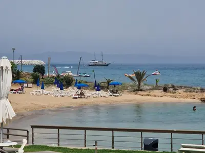 a beach with chairs and a boat in the water at PERNERA 33 Beach House in Protaras