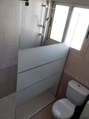 a bathroom with a toilet and a shower with a window at KapparisVilla in Paralimni