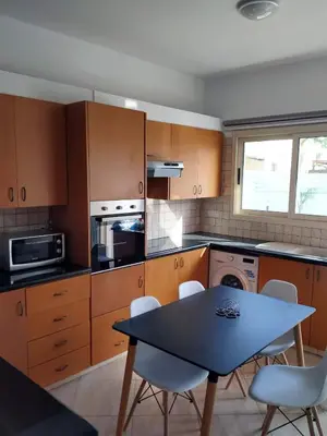 a kitchen with wooden cabinets and a table and chairs at KapparisVilla in Paralimni