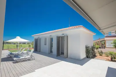 a white house with two chairs and an umbrella at Leda Villa in Protaras