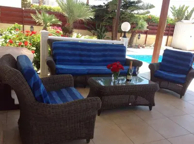 a patio with chairs and a table and a pool at Carolyn Villa is a Luxury 4-Bedroom Villa with Private Pool in Ayia Napa in Ayia Napa