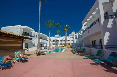 a group of people sitting in chairs by a swimming pool at Anthea Hotel Apartments in Ayia Napa