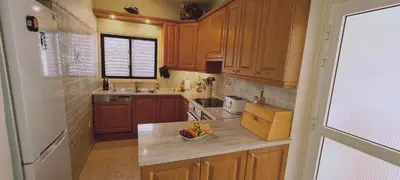 a kitchen with wooden cabinets and a bowl of fruit on a counter at STAY Swallow's Nest Villa in Ayia Napa
